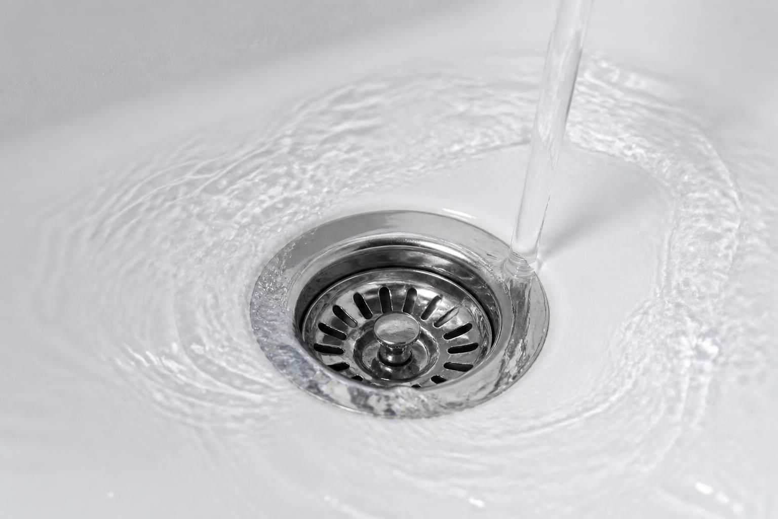Clean sink drain with clear water flow after unblocking.